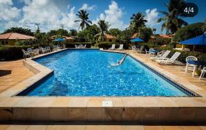 una piscina en un complejo con sillas y sombrillas en Pousada Caminho do Mar, en Imbassai