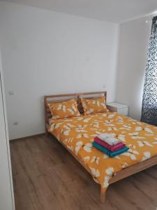 1 dormitorio con 1 cama con sábanas de color naranja y suelo de madera en Oaza de liniște,THERME&Airport en Corbeanca