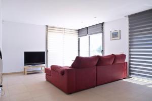 ein rotes Sofa im Wohnzimmer mit einem TV in der Unterkunft WELCS VILLA MODERNA 031 EMP con Piscina y Vistas in Llança