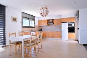 eine Küche mit einem weißen Tisch und Holzschränken in der Unterkunft WELCS VILLA MODERNA 031 EMP con Piscina y Vistas in Llança