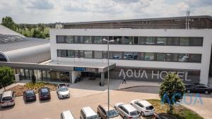 a parking lot in front of a building with parked cars at Aqua Hotel in Kecskemét