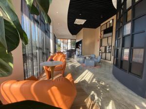 a lobby with orange chairs and tables in a building at OTEL Hotel Suite in Sibu