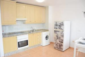 eine Küche mit gelben Schränken und einem weißen Kühlschrank in der Unterkunft Bonito y tranquilo apartamento en Los Abrigos in Los Abrigos