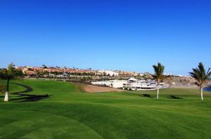 a green golf course with palm trees and a marina at Bahia Meloneras Vista Golf in Meloneras