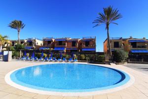 a swimming pool in a resort with palm trees and buildings at Bahia Meloneras Vista Golf in Meloneras