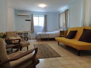 sala de estar con sofá amarillo y cama en Galilee Bedouin Camplodge en Tabash