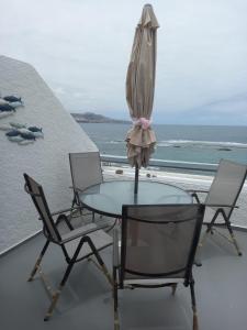 a glass table with chairs and an umbrella on a balcony at Las Canteras Sunset Beachfront in Las Palmas de Gran Canaria