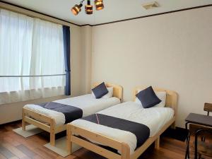 Duas camas num quarto com uma janela em Tabist Business Hotel Chitose Kashiwazaki em Kashiwazaki