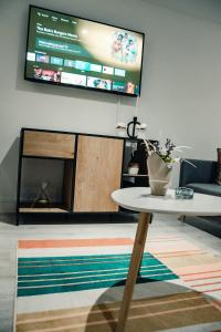 a living room with a table and a flat screen tv at Bv Comfy Basement Apartment At Conditioning House in Bradford