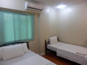 two beds in a small room with a window at Casa Saudade Condotels and Transient Rooms in Olongapo