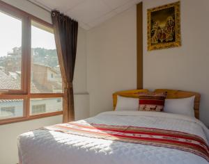 ein Schlafzimmer mit einem Bett und einem großen Fenster in der Unterkunft Yupay Inn Hotel in Cusco