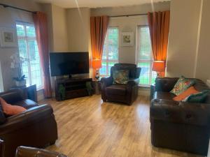 a living room with two couches and a flat screen tv at Sperrin View Apartment (Ground Floor) in Draperstown