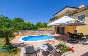 a pool with chairs and an umbrella next to a house at 3 Bedroom Cozy Home In Vodnjan in Vodnjan