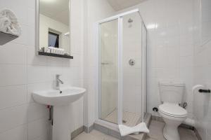 uma casa de banho com um chuveiro, um WC e um lavatório. em The Park Lodge Hotel em Pretoria