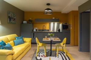 a living room with a yellow couch and a table and chairs at Villa Seyal - avec piscine - jacuzzi - sauna & climatisation in Le Mans