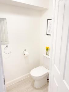 a white bathroom with a toilet and a vase of flowers at Tudors eSuites 3 Bed House Garden & Netflix in Birmingham