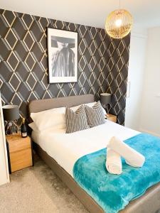 a bedroom with a large bed with a blue blanket on it at Tudors eSuites 3 Bed House Garden & Netflix in Birmingham