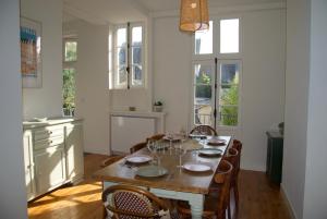 een eetkamer met een tafel, stoelen en ramen bij Villa France Gall in Trouville-sur-Mer