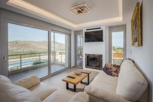 a living room with a white couch and a fireplace at Villa Of the Hill with Heated Pool, BBQ & Kids Playground in Kavoúsion
