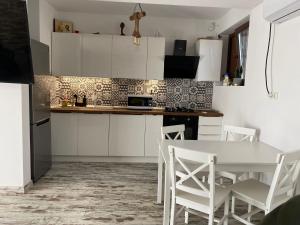 a kitchen with white cabinets and a table and chairs at Casa Maria in 2 Mai