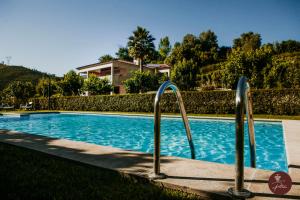 una piscina con barras de metal frente a una casa en Casa da Quinta - Quinta da Portela en Terras de Bouro