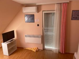a living room with a television and a window at Gitta Apartmanház in Zalakaros