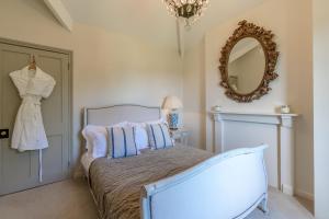 een slaapkamer met een bed en een spiegel aan de muur bij Peartree Cottage in Chippenham