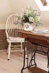 a table with a vase of flowers and a chair at Annelies'Place to B& B in Maastricht