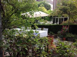 a garden with two white chairs and an umbrella at Annelies'Place to B& B in Maastricht