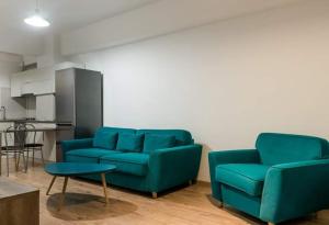 a living room with two blue chairs and a table at CONFORT' by J in Iaşi