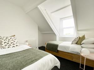 a white bedroom with two beds and a window at 89 St John's Road Terrace House in Newcastle upon Tyne