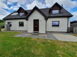 een groot wit huis met een tuin bij Teaghlach, Cairngorms - Escape Cottages Scotland in Newtonmore