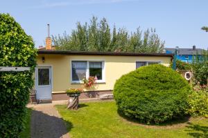 una casa gialla con giardino e cespugli di Ferienbungalow Kroeslin a Kröslin Altre 19 foto