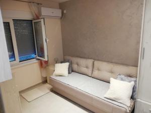 a couch in a small room with two windows at Extra Fruske in Vrdnik