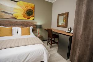 Schlafzimmer mit einem Bett und einem Schreibtisch mit einem Spiegel in der Unterkunft Vinique Guesthouse in Nelspruit