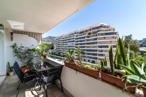 a balcony with a table and chairs and a large building at Apartamento Puerto Azul in Marbella
