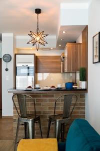 a kitchen with a bar with three chairs and a table at Millo Apartament IMPERO z Parkingiem in Poznań