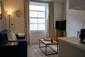 a living room with a couch and a table and a window at K Suites - Wellington Street 1 in Gloucester