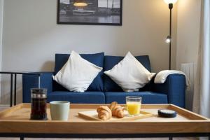 una mesa de centro con una bandeja de bollería en un sofá azul en K Suites - Wellington Street 1 en Gloucester