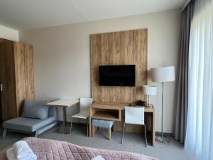 a hotel room with a desk and a tv at Aparthotel Apartamenty Czarna Góra 112 in Sienna