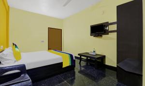 a bedroom with a bed and a tv and a table at Itsy By Treebo - Aravind Premiere Kushalnagar in Madikeri
