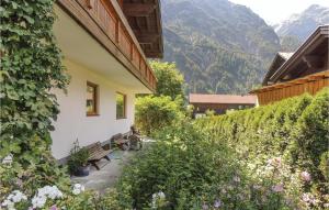 a building with a bench in a garden with mountains at 7 Bedroom Cozy Apartment In Holzgau in Holzgau