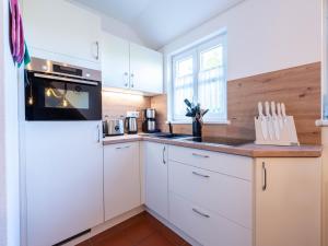 eine Küche mit weißen Schränken und einem schwarzen Gerät in der Unterkunft Feriendorf Rugana - Komfortplus Ferienwohnung mit 1 Schlafzimmer B12 in Dranske + 2 Fotos