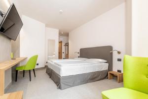 a bedroom with a bed and a desk and a green chair at Curt di Clement Eco Mobility Hotel in Tirano