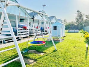 a swing in a yard next to a house at Domki Kapitana in Bobolin