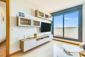 a living room with a tv and a large window at Home2Book Charming Urban Siete Palmas in Las Palmas de Gran Canaria