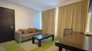 Hotel Trinitarias Suites في Barquisimeto: غرفة معيشة مع أريكة وطاولة