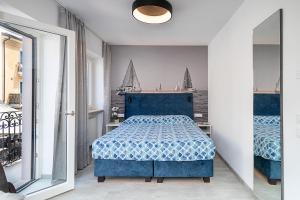 a bedroom with a blue bed and sailboats on the wall at BAUR SUITE - Regarda Travel in Bardolino