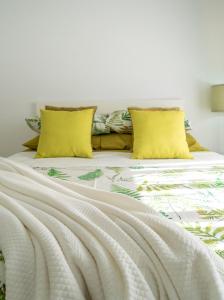 a bed with white sheets and yellow pillows at Sun, Sea, Beach Costa Calida Spain Henrys Apartment in Águilas