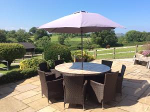 a table and chairs with an umbrella on a patio at Ty Bach, 1 bedroom home with hot tub and views in Bettws-yn-Rhôs